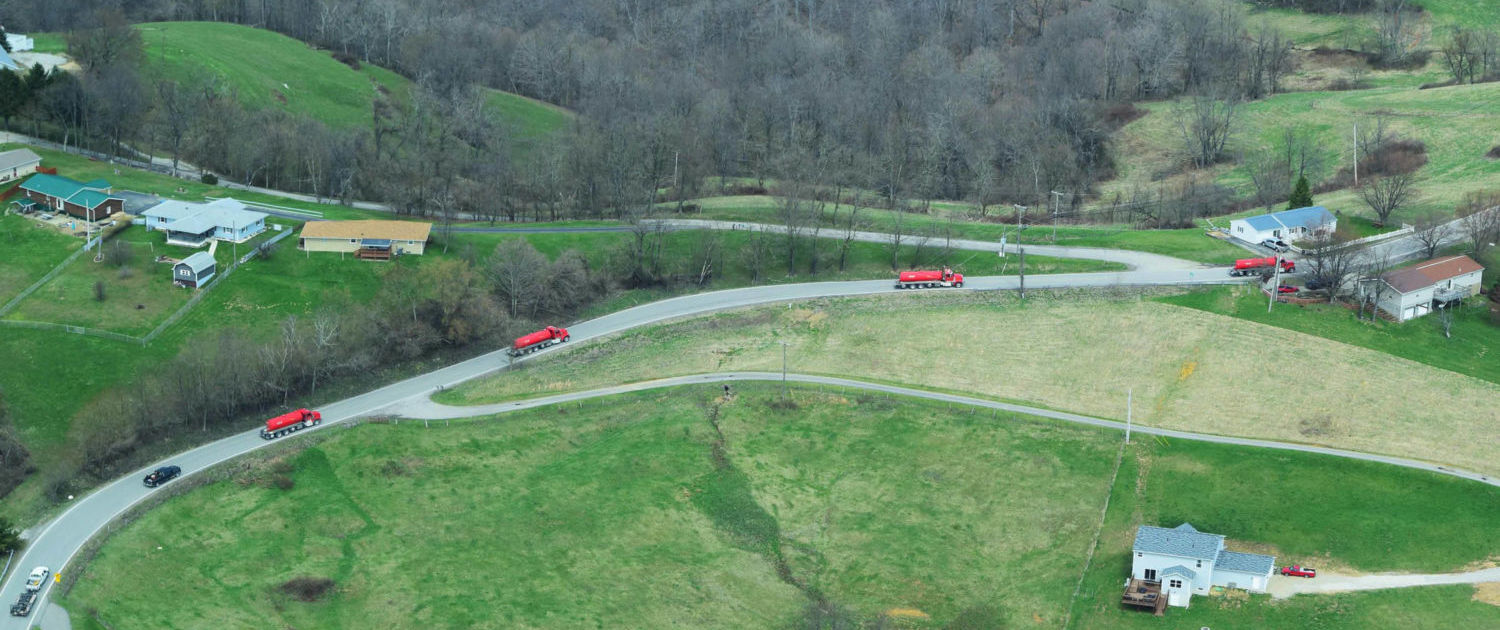 Aerial view of red brine haulers traveling on rural roads near homes in Moundsville, West Virginia.