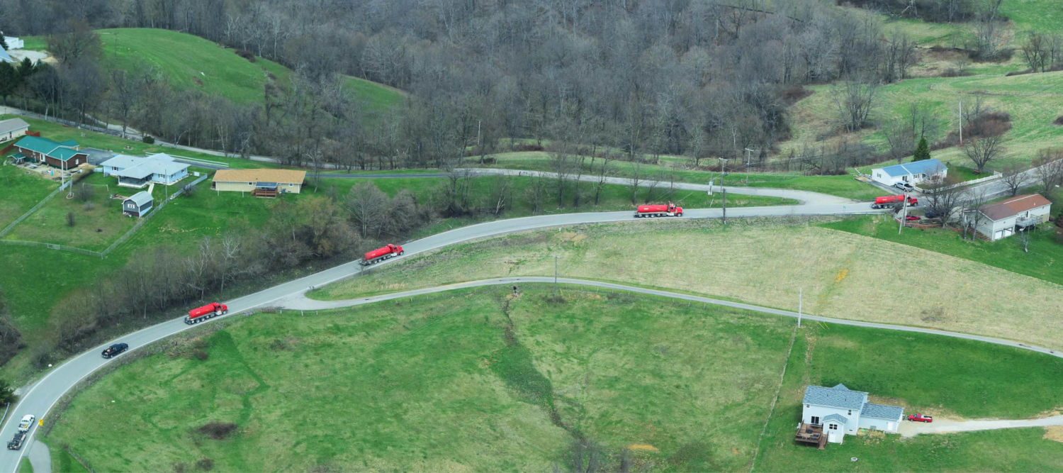 Aerial view of red brine haulers traveling on rural roads near homes in Moundsville, West Virginia.